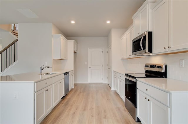 kitchen featuring white cabinetry, appliances with stainless steel finishes, sink, and light wood-type flooring