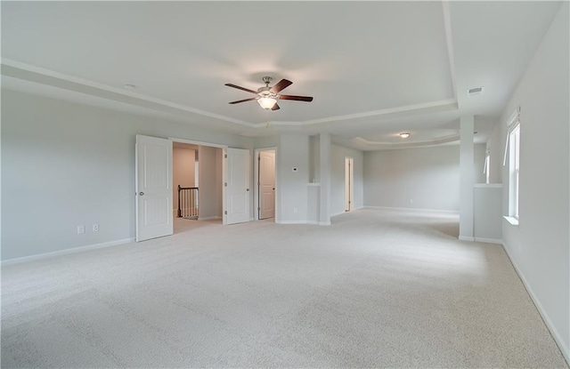 unfurnished room featuring ceiling fan, a tray ceiling, and light carpet