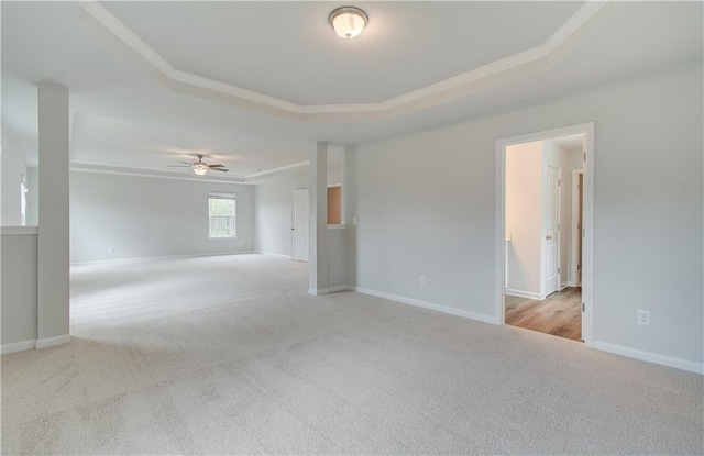 spare room featuring light carpet, crown molding, ceiling fan, and a raised ceiling