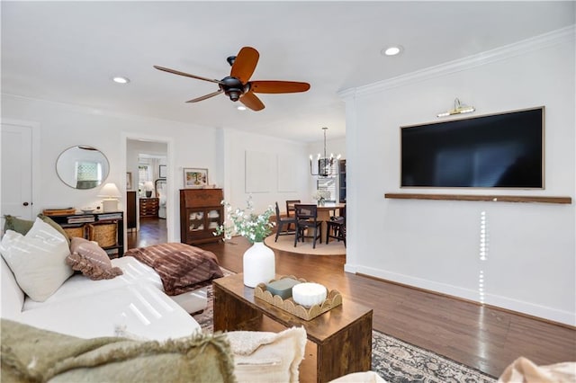 living room with ceiling fan with notable chandelier, dark hardwood / wood-style flooring, and crown molding