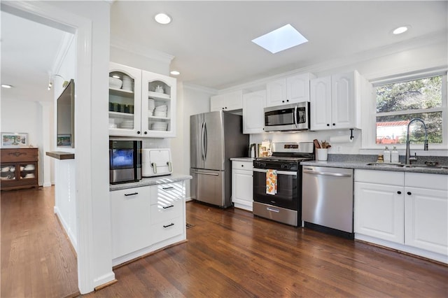 kitchen featuring white cabinets, stainless steel appliances, a skylight, dark hardwood / wood-style flooring, and sink