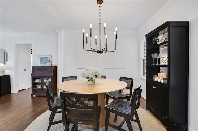 dining room with dark wood-type flooring, a notable chandelier, and crown molding