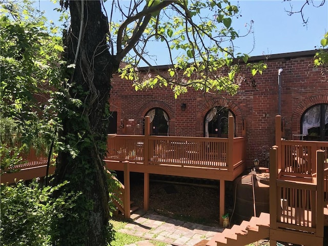 back of house with brick siding and a deck