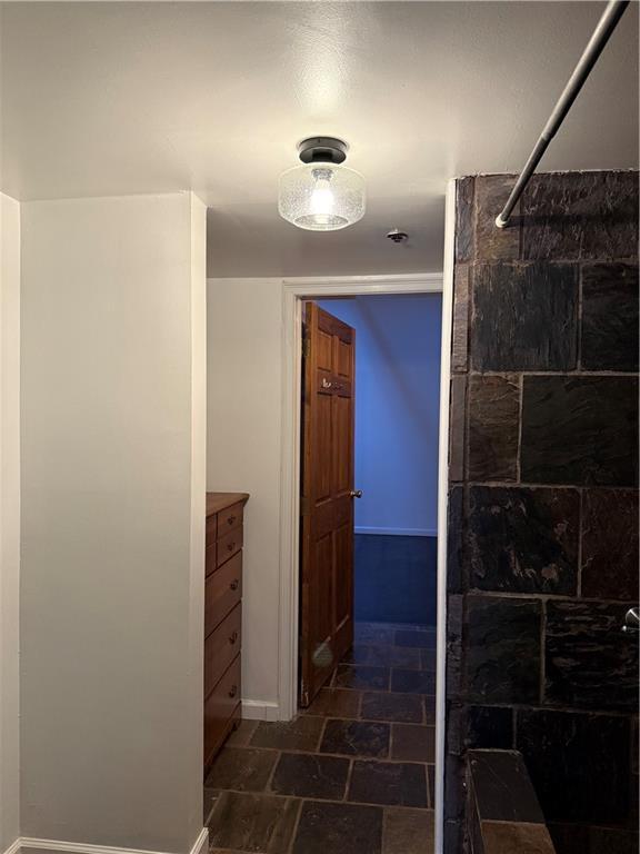 bathroom featuring stone tile floors and tiled shower