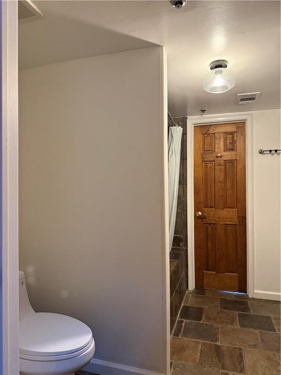 full bath with visible vents, baseboards, toilet, and stone tile floors