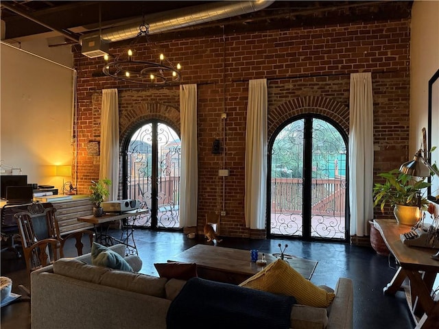 interior space featuring french doors, arched walkways, brick wall, and a chandelier