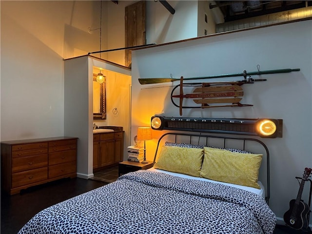 bedroom featuring connected bathroom, a high ceiling, baseboards, and a sink