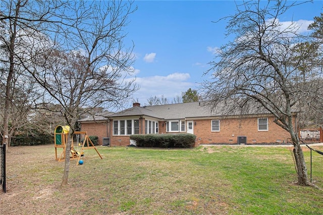 back of property featuring crawl space, a chimney, a lawn, and a playground