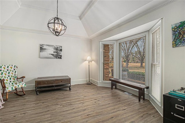 living area featuring a chandelier, crown molding, baseboards, and wood finished floors