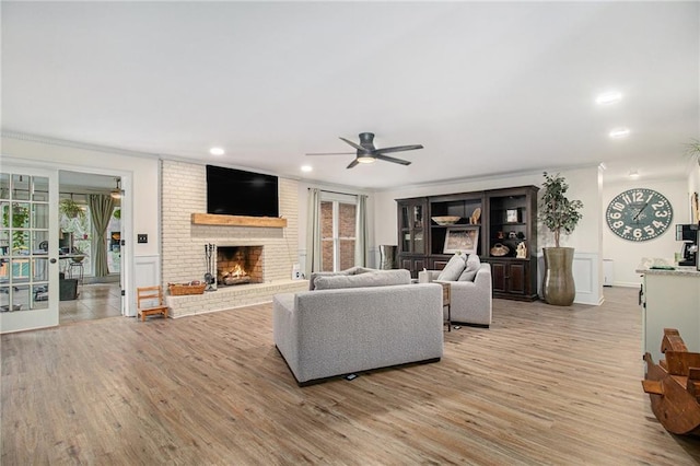 living room featuring ceiling fan, recessed lighting, a brick fireplace, and light wood-style floors