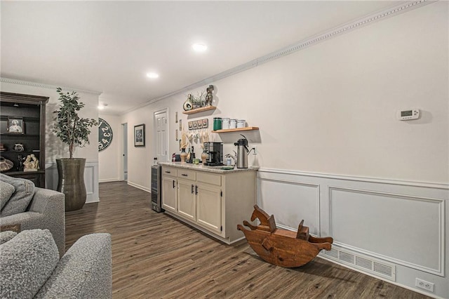 bar featuring beverage cooler, dark wood-type flooring, visible vents, ornamental molding, and wainscoting