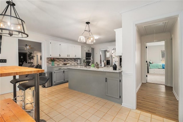 kitchen featuring tasteful backsplash, a peninsula, gray cabinets, stainless steel appliances, and light tile patterned flooring