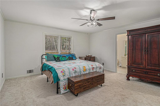 bedroom with ceiling fan, light colored carpet, visible vents, baseboards, and ensuite bath