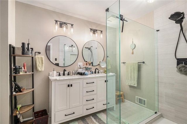 bathroom with visible vents, a sink, a shower stall, and double vanity