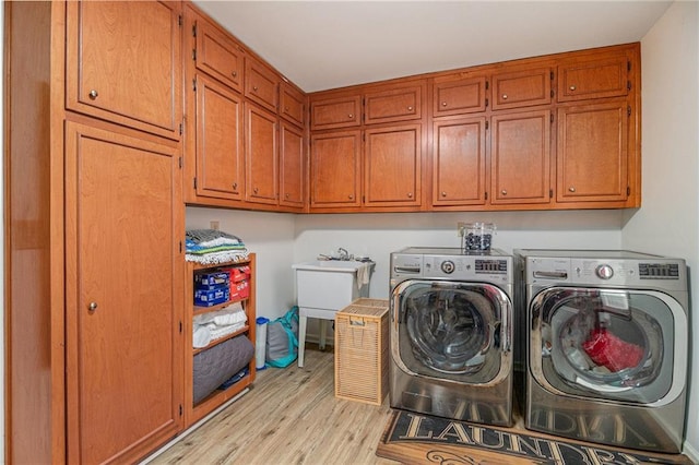 laundry room with cabinet space, light wood-style flooring, and separate washer and dryer