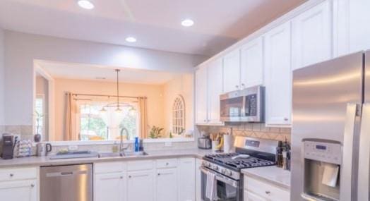 kitchen featuring sink, white cabinetry, decorative light fixtures, stainless steel appliances, and backsplash