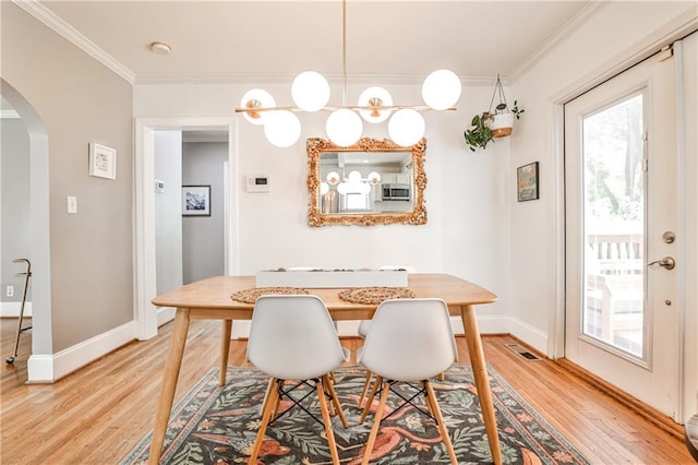 1136 Moreland Pl SE, Atlanta, GA 30316 - dining area featuring arched walkways, light wood-style floors, crown molding, healthy amount of natural light, and baseboards