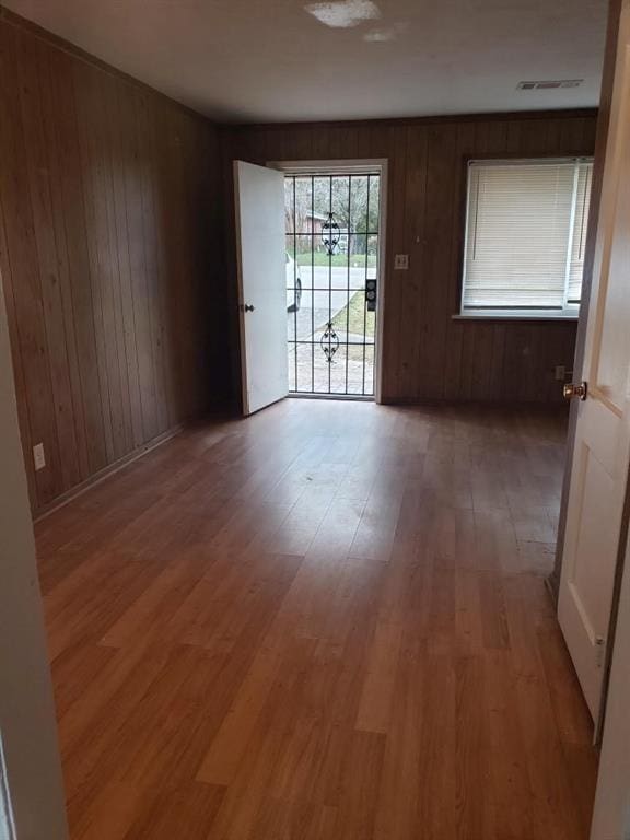 empty room featuring wood walls and light wood-type flooring