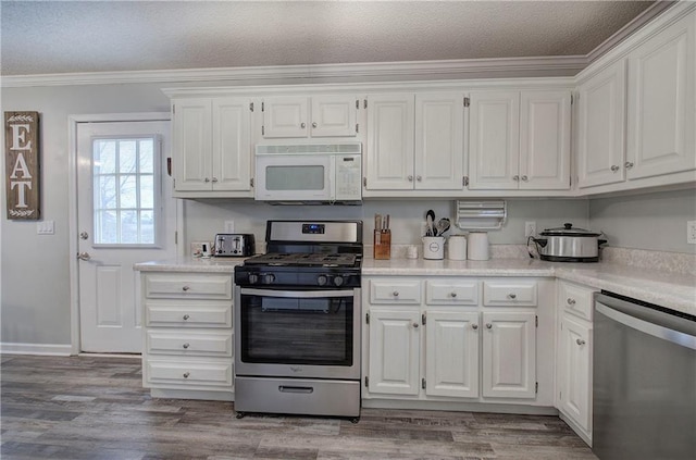 kitchen with stainless steel appliances, light wood-style floors, light countertops, and white cabinets