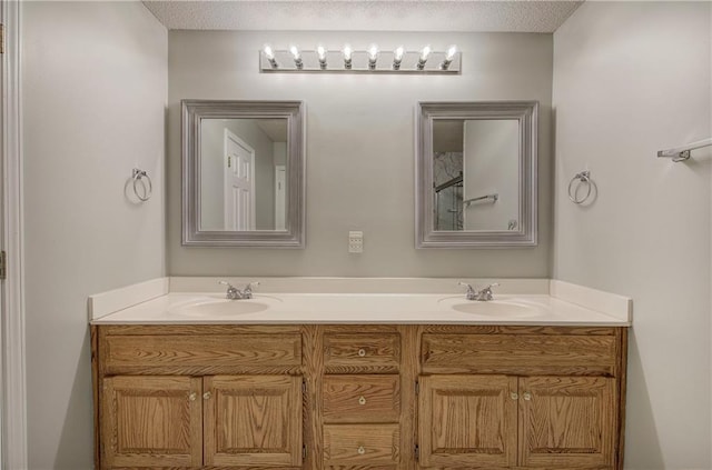 full bathroom with a textured ceiling, double vanity, and a sink