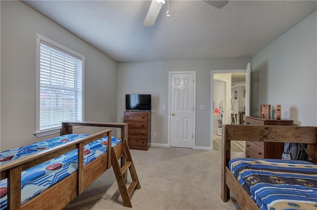 bedroom with a textured ceiling, baseboards, a ceiling fan, and light colored carpet