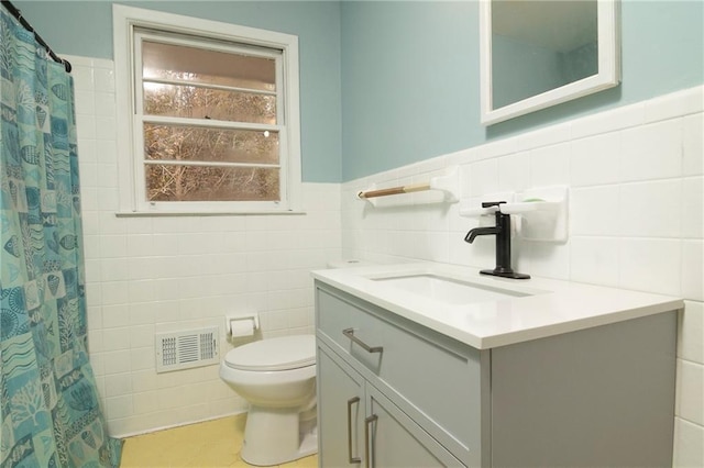 full bathroom with toilet, vanity, visible vents, and tile walls