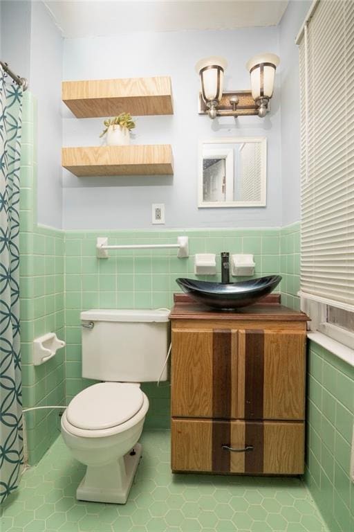 bathroom featuring toilet, a wainscoted wall, tile walls, and vanity