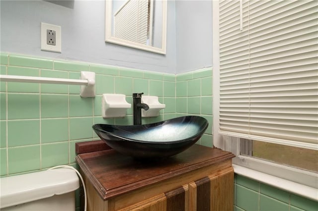 bathroom featuring a wainscoted wall, toilet, tile walls, and vanity