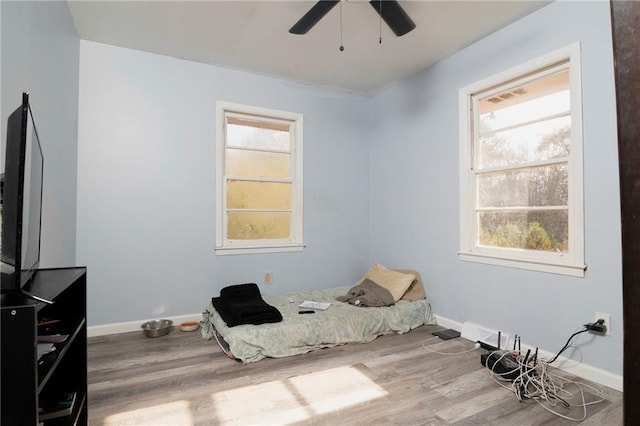 bedroom featuring ceiling fan, baseboards, and wood finished floors