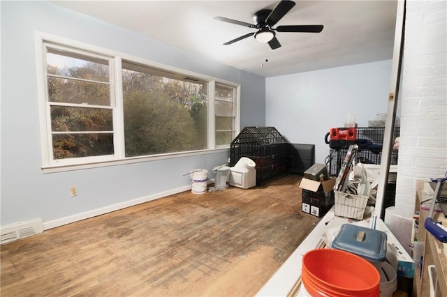 interior space with a ceiling fan, visible vents, baseboards, and wood finished floors