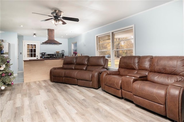 living area featuring a ceiling fan, crown molding, and light wood finished floors