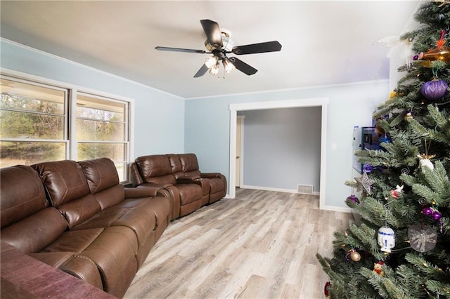 living room featuring visible vents, baseboards, ceiling fan, crown molding, and light wood-style floors