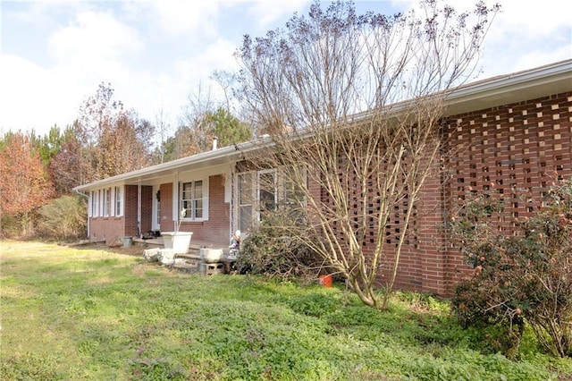 back of property featuring a lawn and brick siding