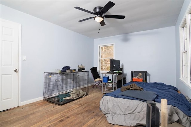 bedroom featuring multiple windows, baseboards, and wood finished floors