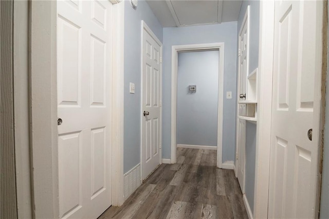 corridor featuring baseboards and wood finished floors