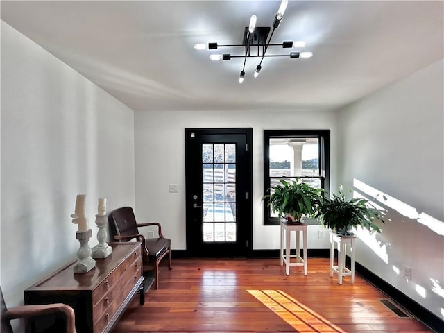 foyer entrance with an inviting chandelier, visible vents, and hardwood / wood-style flooring