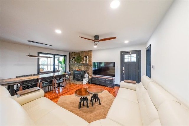 living room featuring a ceiling fan, wood finished floors, recessed lighting, and a stone fireplace