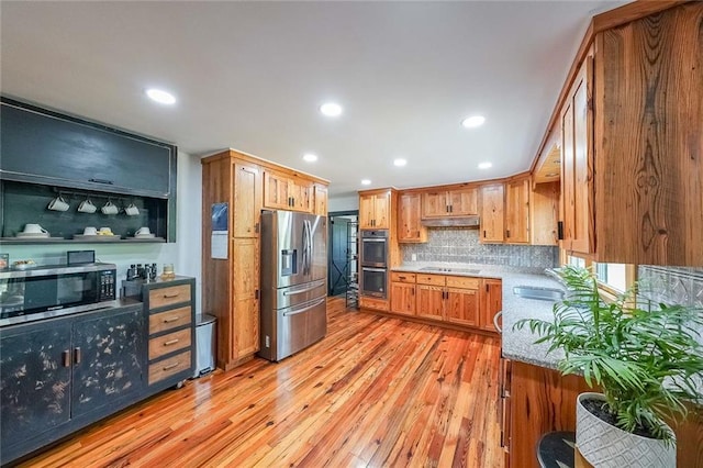 kitchen featuring recessed lighting, light wood-style flooring, stainless steel appliances, under cabinet range hood, and backsplash