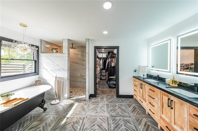 bathroom featuring a freestanding tub, a marble finish shower, double vanity, and a sink