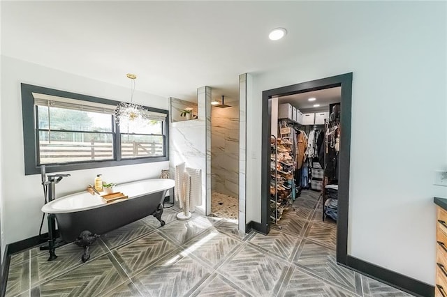 bathroom featuring baseboards, a marble finish shower, recessed lighting, a freestanding tub, and a walk in closet
