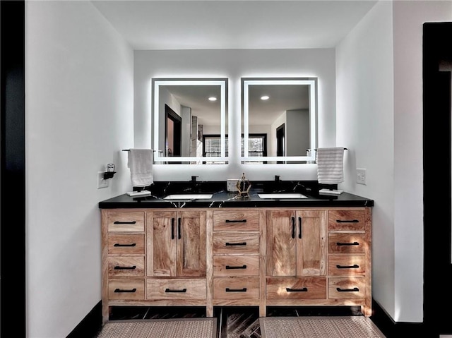 full bath with baseboards, double vanity, and a sink