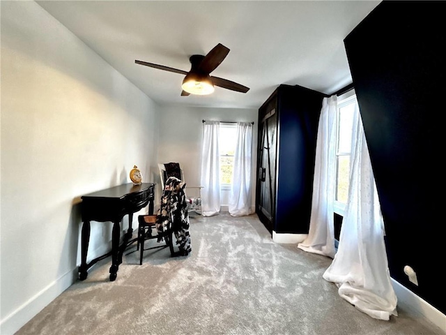 carpeted home office with baseboards, ceiling fan, and plenty of natural light
