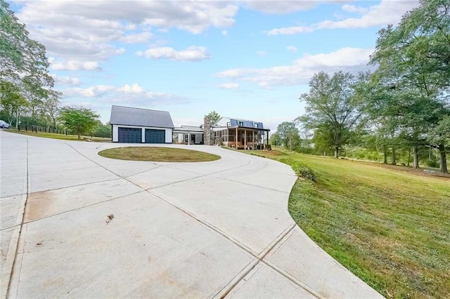 view of front of house featuring a detached garage, concrete driveway, and a front yard