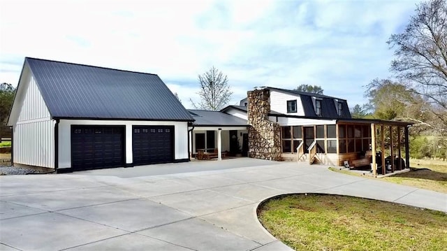 view of front of house with metal roof, concrete driveway, an attached garage, and a sunroom