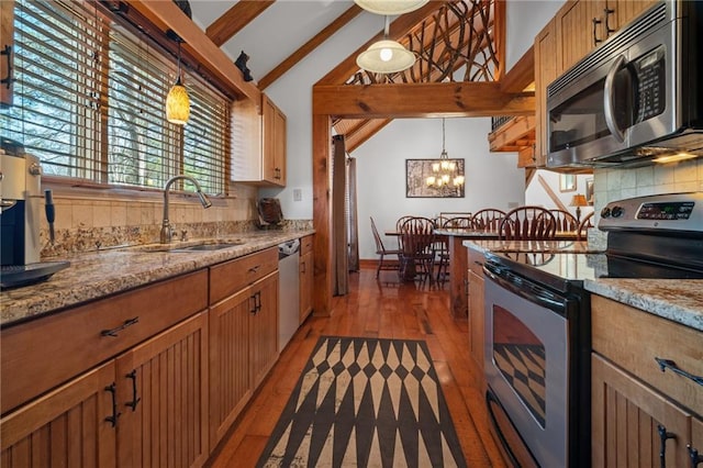 kitchen with decorative light fixtures, light wood-type flooring, lofted ceiling with beams, stainless steel appliances, and a sink