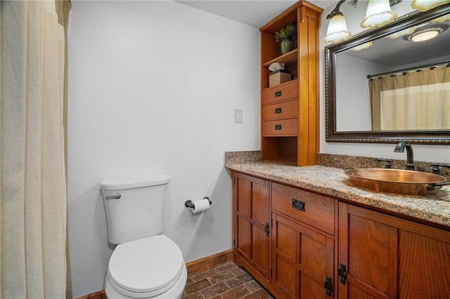 full bathroom with toilet, vanity, and baseboards