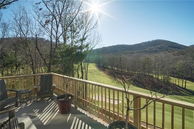 wooden terrace with a mountain view, a view of trees, and a yard