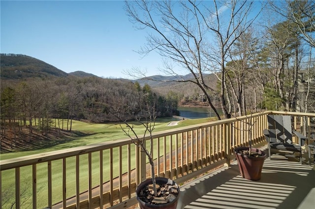 wooden deck with a water and mountain view and a lawn