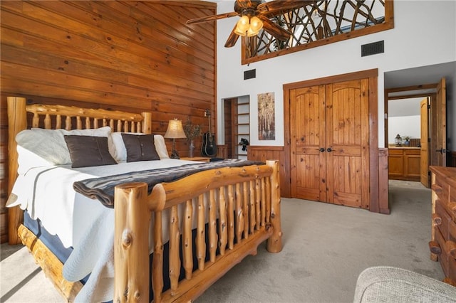 bedroom featuring wooden walls, visible vents, carpet floors, wainscoting, and a ceiling fan