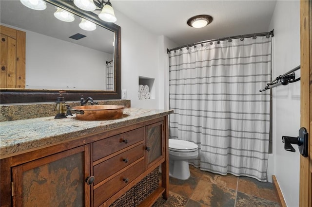 full bath with visible vents, toilet, stone finish floor, a shower with shower curtain, and vanity